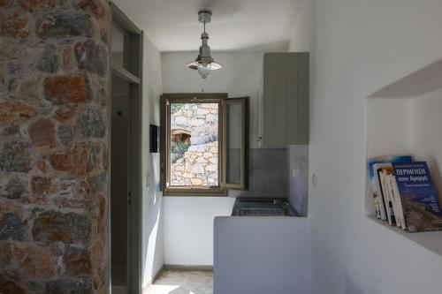 a kitchen with a window and a stone wall at Dimitra Studios in Aegiali
