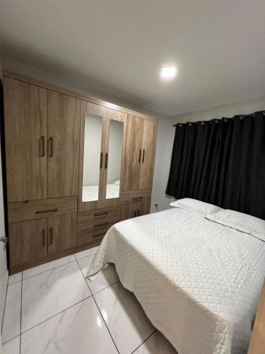 a bedroom with a white bed and wooden cabinets at Apartamento in Campo Largo