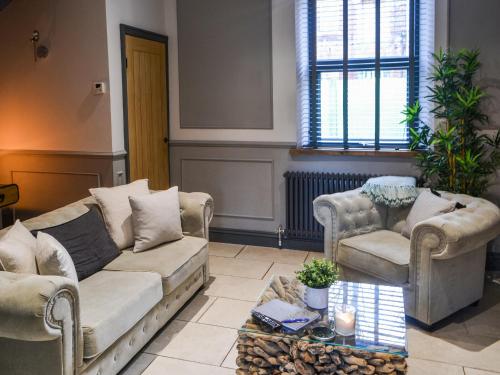 a living room with a couch and two chairs and a table at Copper Cottage in Morpeth