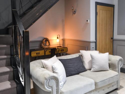 a living room with a white couch and stairs at Copper Cottage in Morpeth