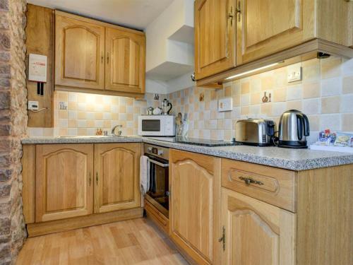 a kitchen with wooden cabinets and a counter top at Bossington- Ukc4921 in Timberscombe