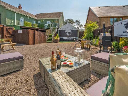 a patio with a table and bottles of wine at Alderfalls - Exclusive Private Pub Experience in Coelbren