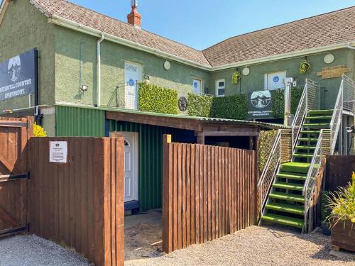 a house with a wooden fence and a gate at Alderfalls - Exclusive Private Pub Experience in Coelbren