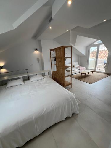 a white bedroom with a large bed and a window at I AM La Posada Hotel and Apartment in Benalmádena