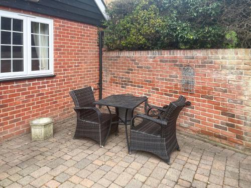a table and four chairs sitting next to a brick wall at The Cottage in Castle Hedingham