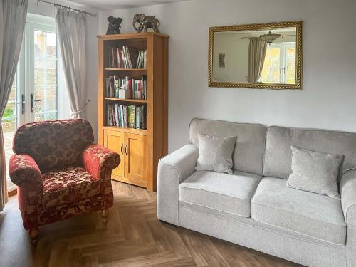 a living room with a couch and a chair and a mirror at The Cottage in Castle Hedingham