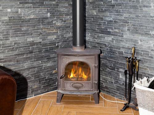 a wood stove in a room with a brick wall at One Eden Cottage - Ukc6253 in Linlithgow