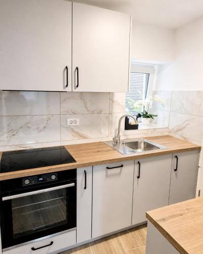 a kitchen with white cabinets and a sink at Apartment Nero in Izola