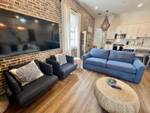a living room with blue couches and a brick wall at Harbor House Penthouse- B in Key West