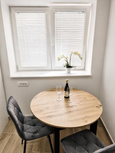 a wooden table with two wine glasses and a vase with flowers at Apartment Nero in Izola