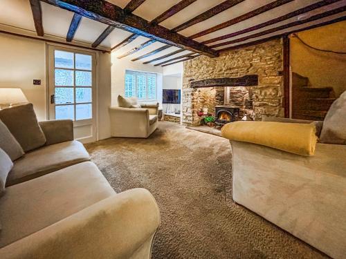 a living room with couches and a stone fireplace at Hailey Cottage in Chipping Norton