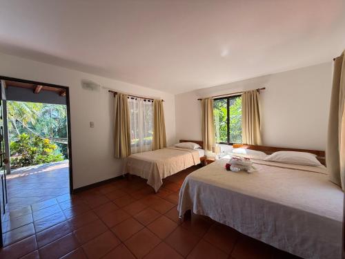 a bedroom with two beds and a large window at Hotel El Jardin in Montezuma