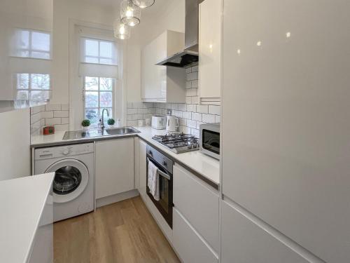 a white kitchen with a washer and dryer at Joss Bay Days in Broadstairs