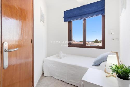 a small bedroom with a bed and a window at Villa FLEUR in Cala en Porter