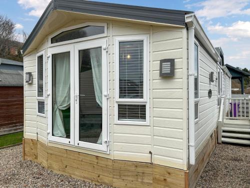 a white cabin with a window in a yard at The Meadow - Uk51411 in Brechin
