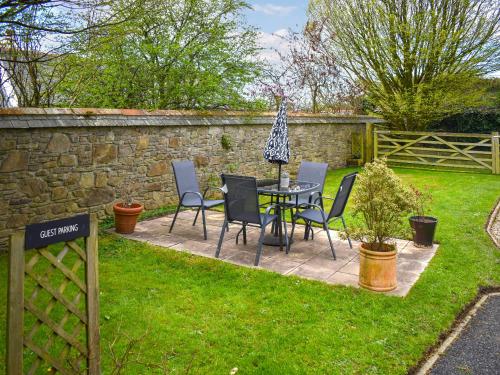 a garden with a table and chairs and a stone wall at Little Gubbs in West Buckland
