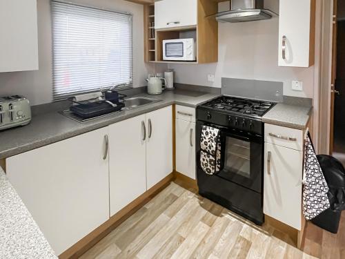a kitchen with white cabinets and a black stove at The View in Stranraer