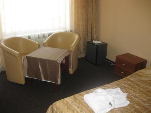 a hotel room with two beds and a table and chairs at Hotel Complex Zelenyi Gai in Kopachuvka