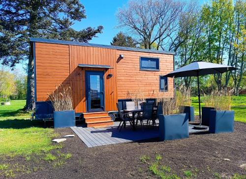 ein winziges Häuschen mit einem Tisch und einem Sonnenschirm in der Unterkunft Tinyhouse WeserNest in Sandstedt