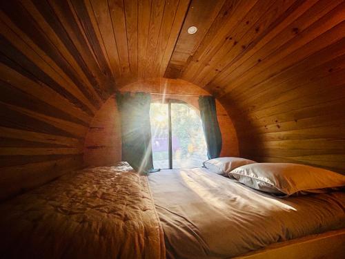 a large bed in a wooden room with a window at Rêve de Plume in Beaumont