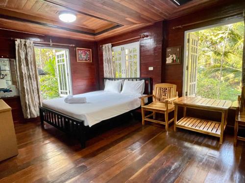a bedroom with a bed and a table and windows at Samnaree Garden House in Ban Phae Mai