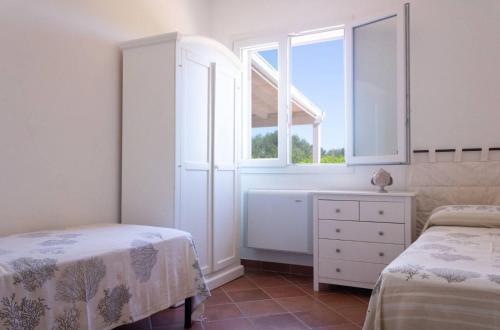a white bedroom with two beds and a window at Villa Selas in Leporano Marina