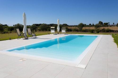 a large swimming pool with chairs and umbrellas at Villa Selas in Leporano Marina