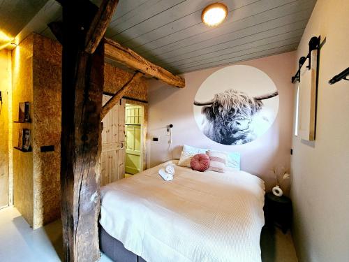 a bedroom with a bed with a bull on the wall at B&B De Emmer in Noord-Sleen