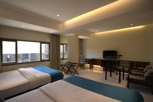 a hotel room with two beds and a flat screen tv at Hotel Prince, Bhuj in Bhuj