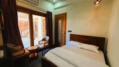 a bedroom with a bed and a chair and a window at Yes Hotel By The Ganges Rishikesh in Rishīkesh