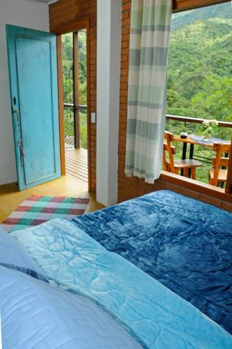 a bedroom with a bed and a balcony with a view at Estalagem Terramauá in Visconde De Maua