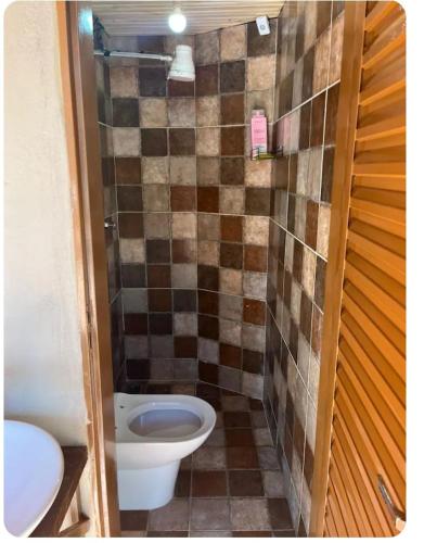 a bathroom with a toilet and a tiled wall at Recanto da harmonia in Ribeirão Preto