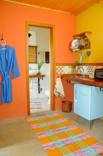 a kitchen with orange walls and a sink and a bathroom at Estalagem Terramauá in Visconde De Maua