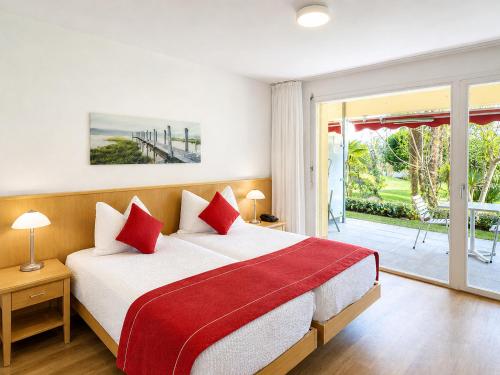 a bedroom with a large bed with red pillows at Parkhotel Emmaus - Casa del Sole in Ascona