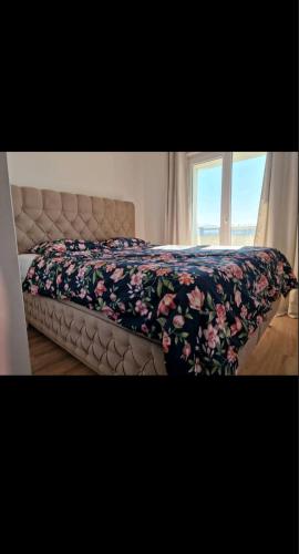 a bed with a floral blanket on it with a window at Opal Skay Apartment in Doboj