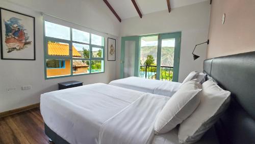 a bedroom with a large white bed and a window at Auka Boutique in Urubamba