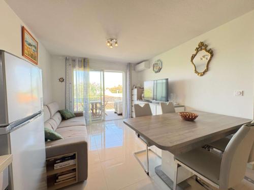 a kitchen and living room with a table and a couch at A 150m de la plage - Coquet appartement pour 4 personnes in Vias