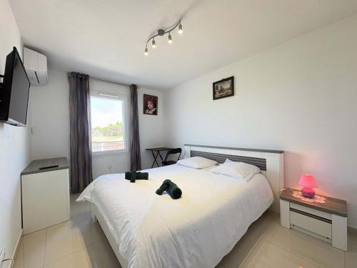 a bedroom with a large white bed and a window at A 150m de la plage - Coquet appartement pour 4 personnes in Vias