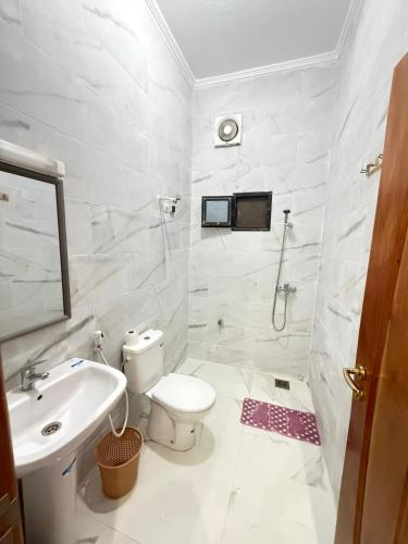 a white bathroom with a toilet and a sink at Dar AL-HANAA in Nouakchott