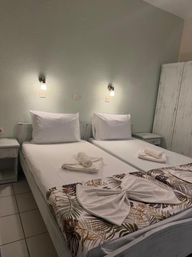 two beds with white sheets and towels on them at Nikis studios in Skala Sotiros