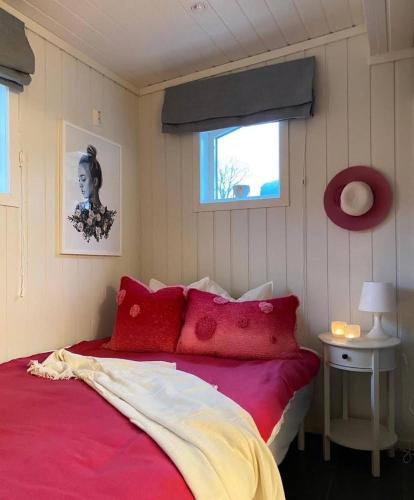 a bedroom with a bed with red pillows and a window at Fjordheart Srbvg 1 in Hyllestad