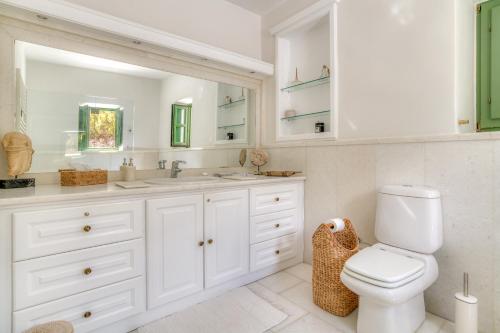 a white bathroom with a toilet and a sink at Villa Thimari in Protorgia