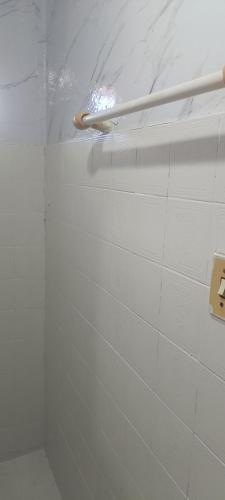 a shower stall with a white tiled wall at Pousada Popular in Barreiras