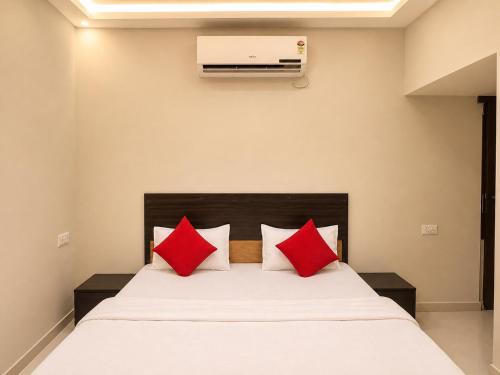 a bedroom with a bed with red pillows at Hotel Tushar in Ahmedabad