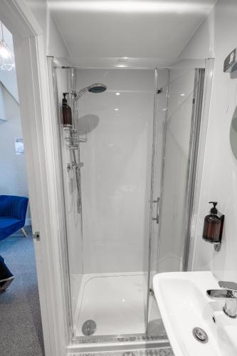 a shower with a glass door next to a sink at Kingsway Guesthouse - A selection of Single, Double and Family Rooms in a Central Location in Scarborough
