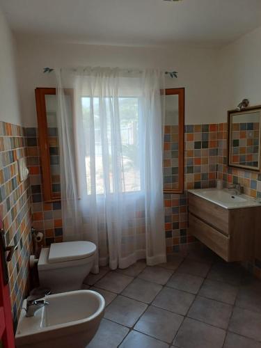 a bathroom with a toilet and a sink and a window at Sole e Sale in Sardegna in Pula