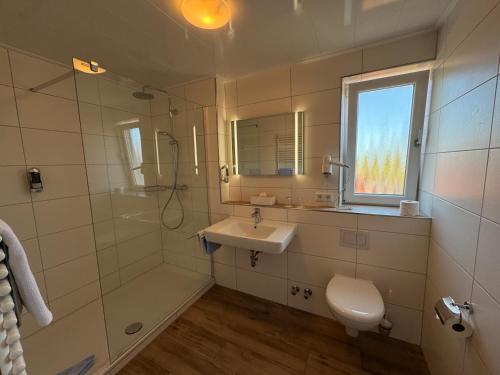a bathroom with a sink and a shower and a toilet at Hotel Zum Hanseaten in Borkum