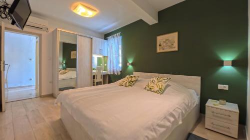 a bedroom with a large bed with green walls at Villa Porto in Mlini