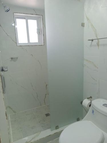 a bathroom with a shower with a toilet and a window at Hacienda Rosarito in Rosarito Beach