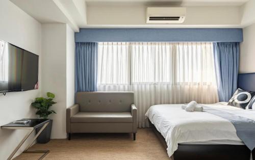 a bedroom with a bed and a chair and a television at R2 condotel tower in Manila